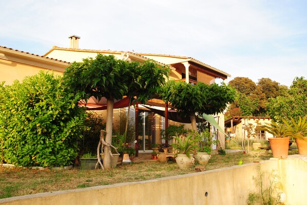 A house with a covered patio area, surrounded by various potted plants and a small garden. - Studio ds Villa in La Campagne av Terrasse, quiet in ALATA (Alata)