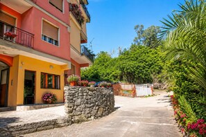 A multi-story building with balconies, a stone wall, and a pathway leading to a gate. - Polly, few steps from the beach -Cinque Terre ,Monterosso. (Monterosso al Mare)