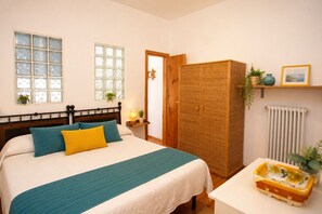 Een slaapkamer met een bed, nachtkastje, kledingkast, raam en radiator.