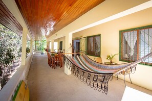 A covered outdoor area with a hammock, wooden ceiling, and a dining table with chairs. - Casa tropical - Located in Playa Guiones - Nosara - Costa Rica (Playa guiones)