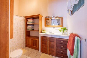A bathroom with a wooden cabinet, a sink, a mirror, and a towel rack. - Casa tropical - Located in Playa Guiones - Nosara - Costa Rica (Playa guiones)