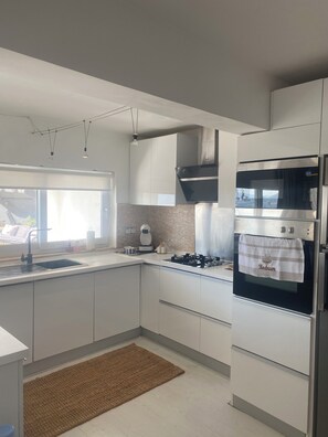 Eine moderne Küche mit weißen Schränken, einem eingebauten Backofen und einem Fenster, das natürliches Licht hereinlässt.
