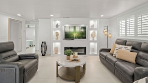 Ein modernes Wohnzimmer mit Ledersofas, einem Couchtisch in der Mitte und einem flachbildfernseher an der Wand.