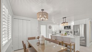 Eine moderne Küche mit weißen Schränken, einem Edelstahlkühlschrank und einer zentralen Kochinsel mit Mikrowelle.