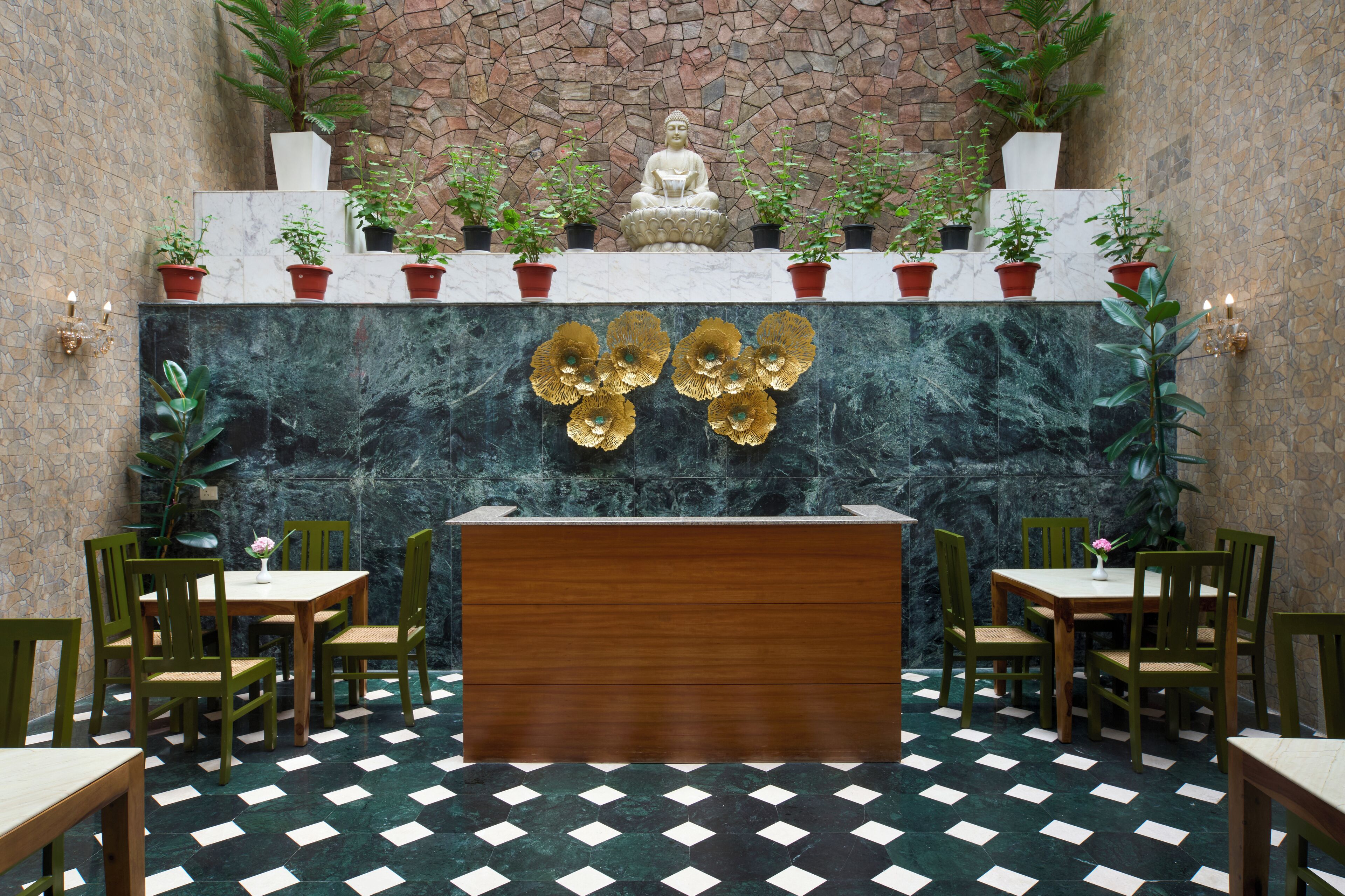 A reception area with a marble wall, a Buddha statue, potted plants, and a checkered floor.