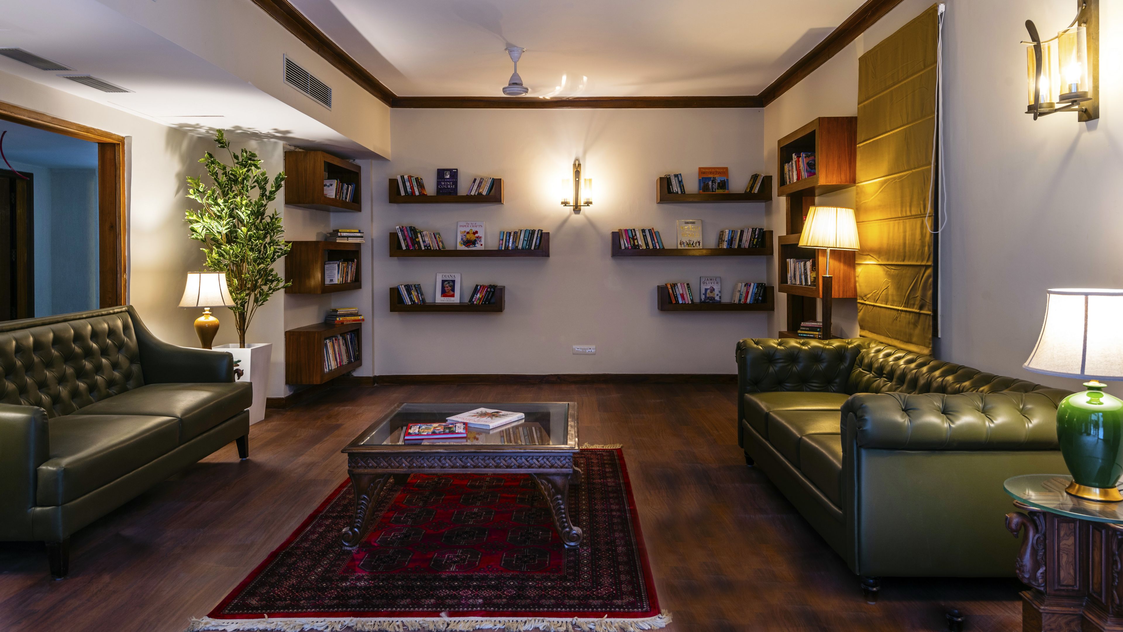 A living room with two leather sofas, a coffee table, a red patterned rug, and bookshelves with books.