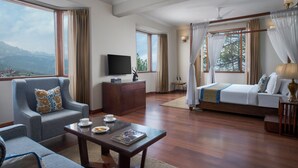 A spacious hotel room with a large bed, a television, a seating area with a coffee table, and a view of the mountains. - 8fold by LaRiSa, Shimla (Shimla)