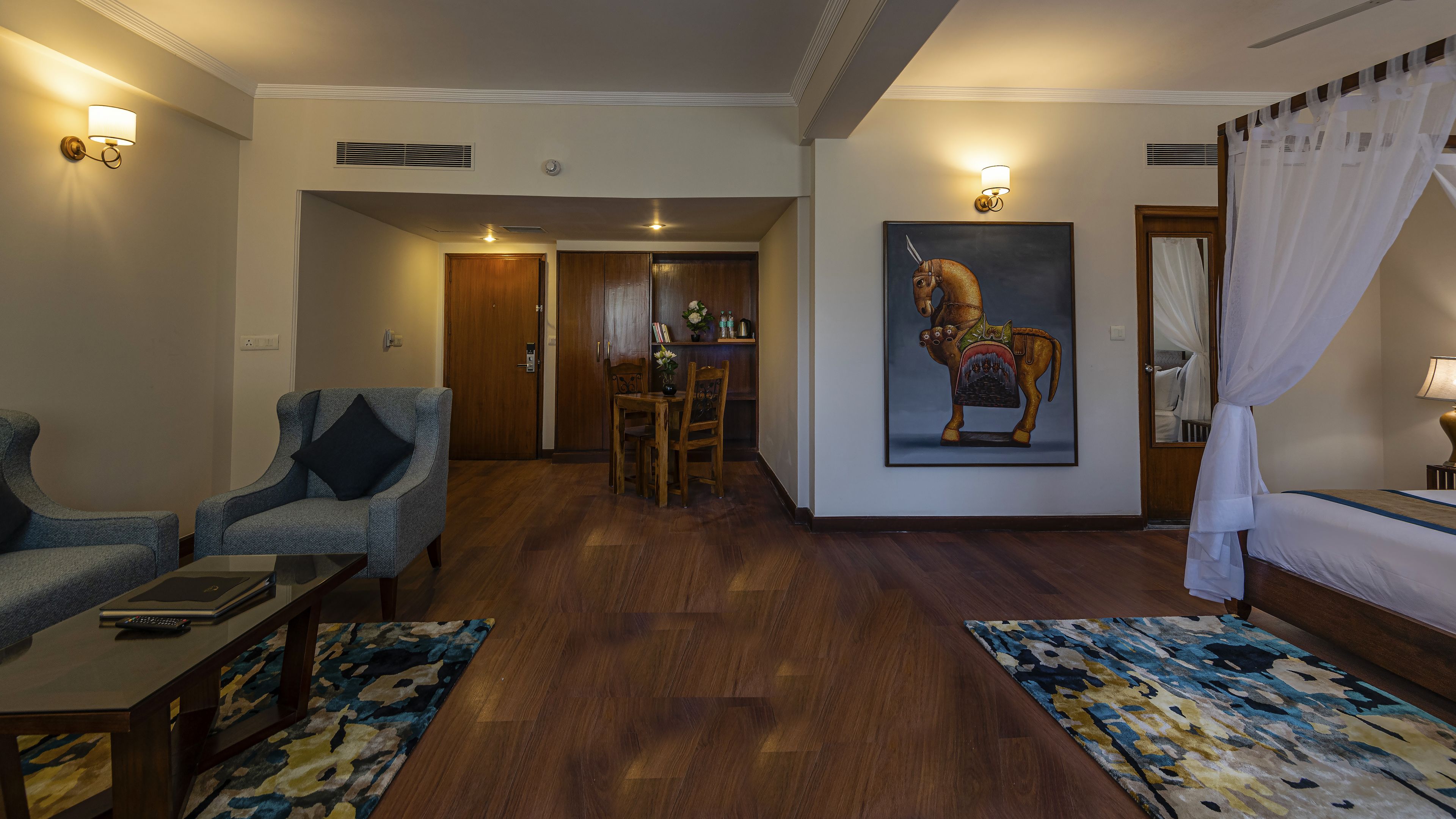 A hotel room with a dining area, a painting of a horse, and a bed with a canopy.