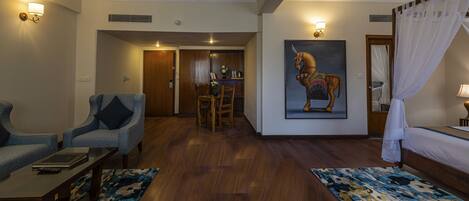 A hotel room with a dining area, a painting of a horse, and a bed with a canopy.