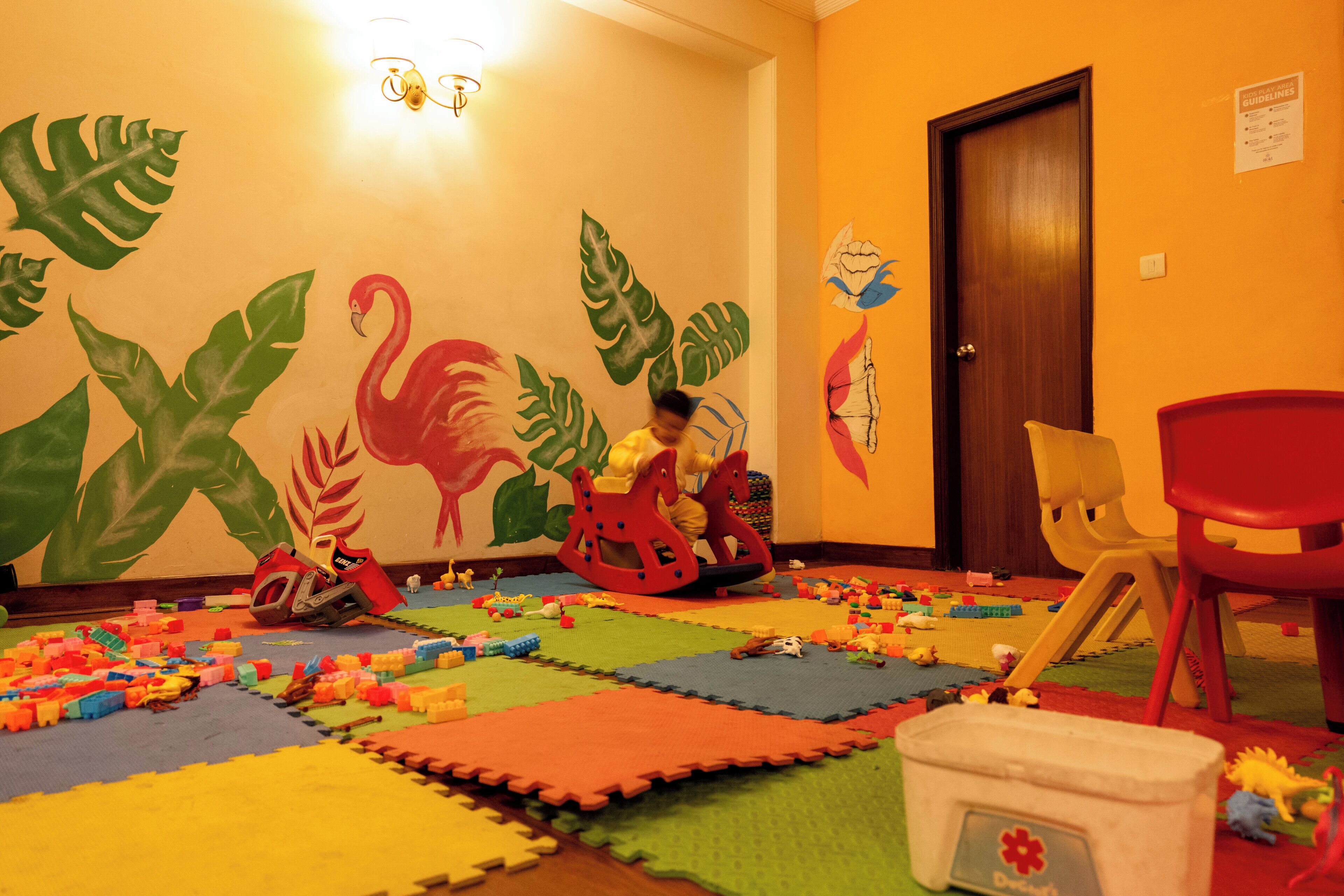 A playroom with colorful play mats, toys, and a child playing.