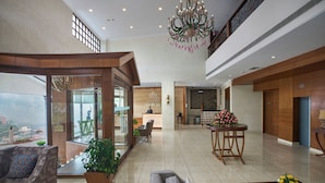 A spacious lobby with a high ceiling, a chandelier, and a seating area with sofas and a coffee table. - 8fold by LaRiSa, Shimla (Shimla)