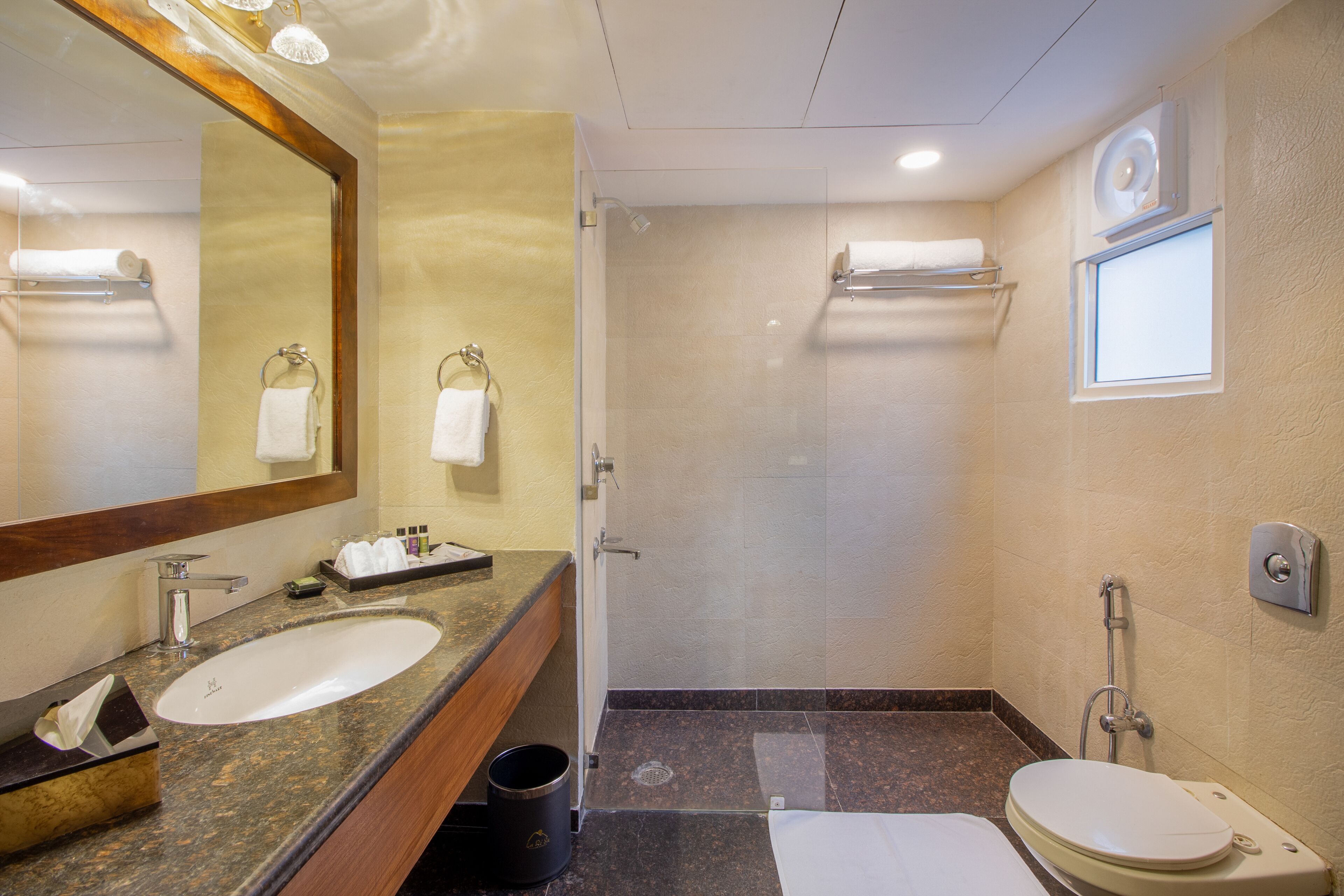 Un baño con lavamanos, espejo, ducha e inodoro.