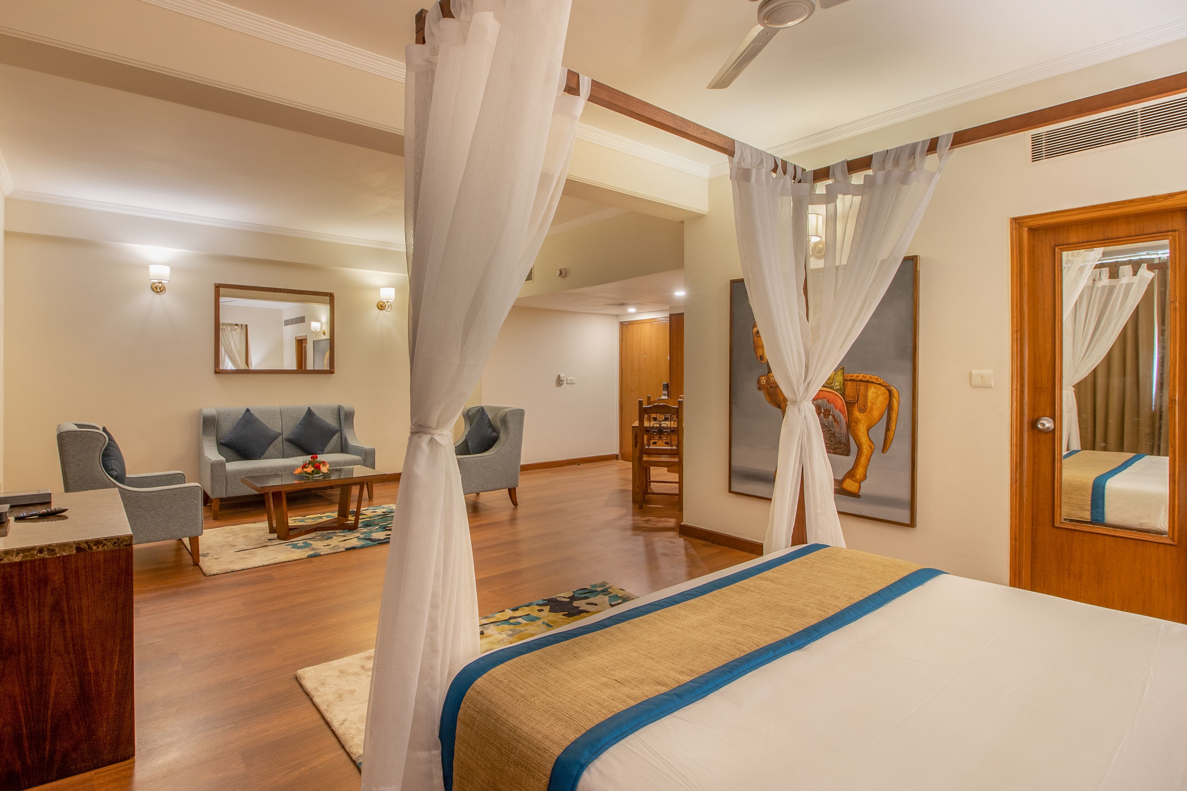 Une chambre d’hôtel avec un lit, un bureau, une chaise, un canapé et un tableau au mur.