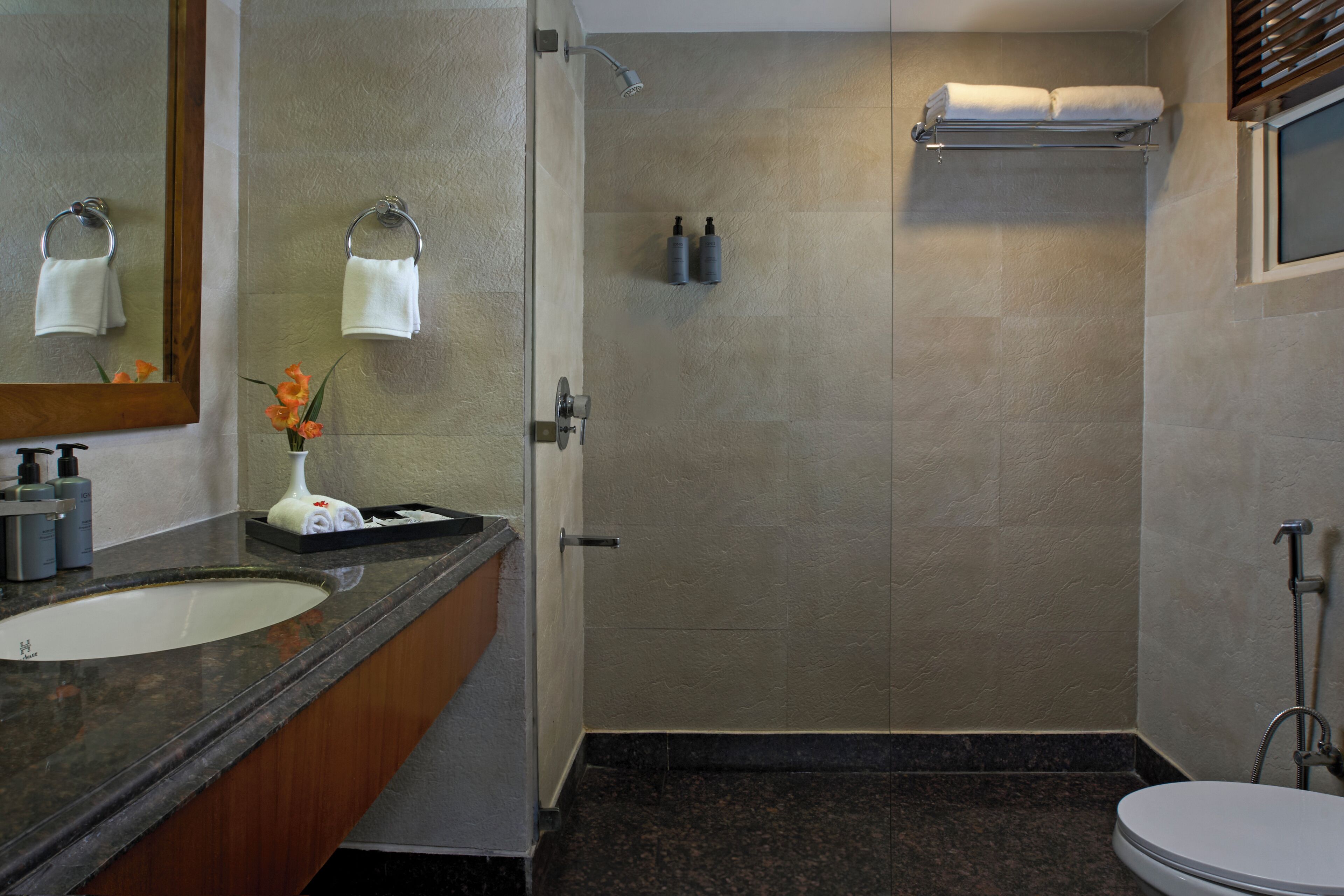 A bathroom with a sink, mirror, shower, and toilet.