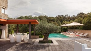 Ett poolområde på taket med solstolar och en pergola.