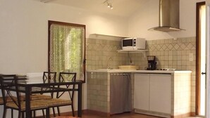 A cozy room with a bed, a dining table, and a kitchenette. - Cottage studio in the countryside (Cavaillon)