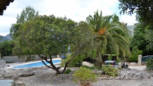 A stone-paved area with a pool, palm trees, and a car parked near a stone wall. - Secluded Finca with Private Pool and Extensive Garden in the Campanet valley  (Campanet)