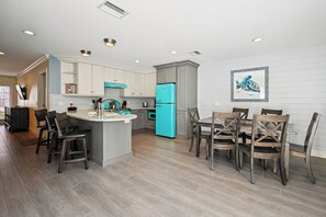 A modern kitchen with a central island, grey cabinets, and a teal refrigerator.