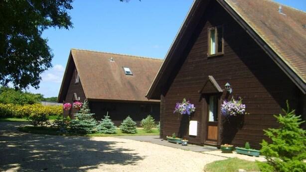 A wooden building with a gravel driveway and flower pots.