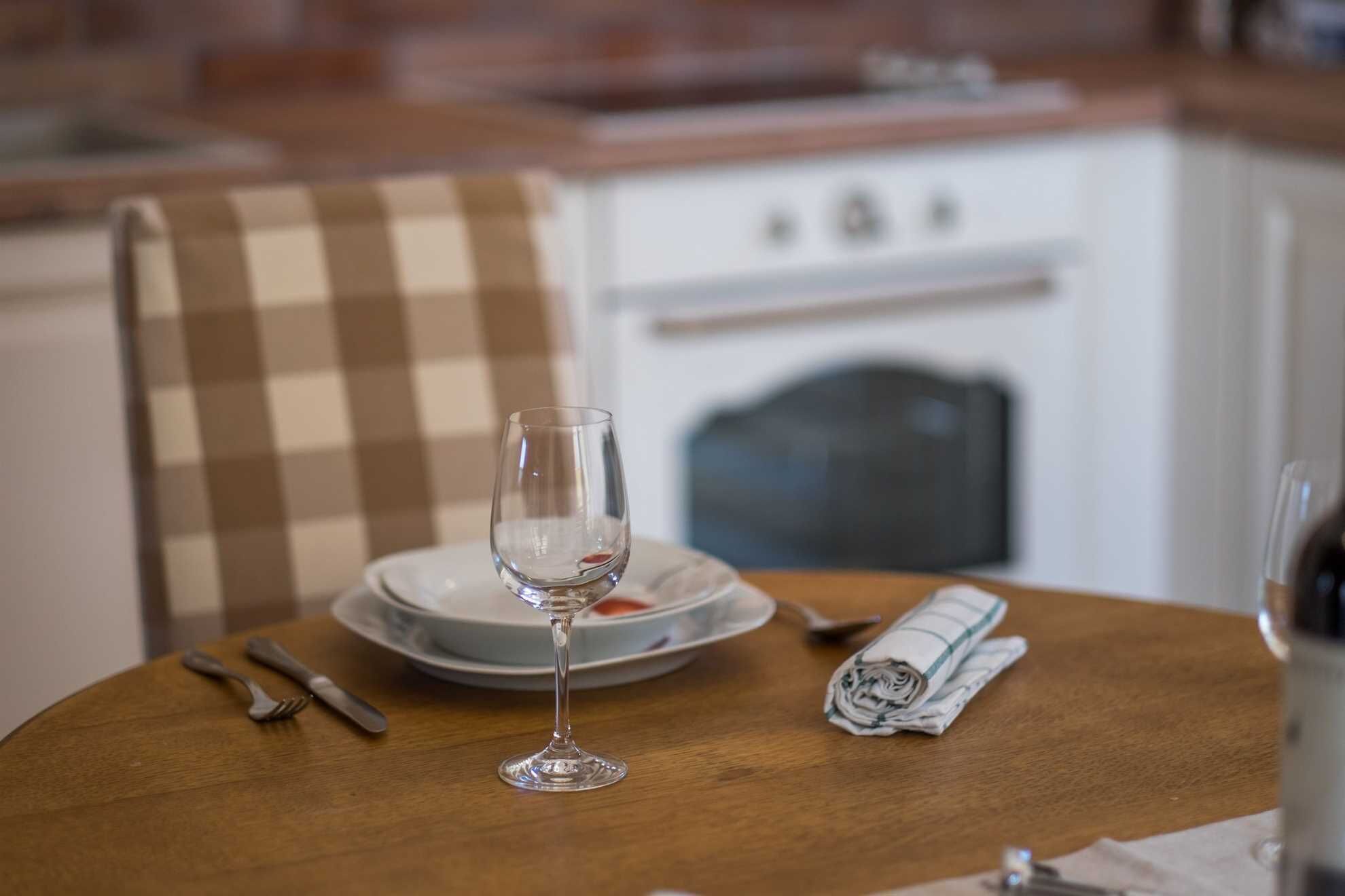 Een eettafel met een glas, een gevouwen servet en een bord.
