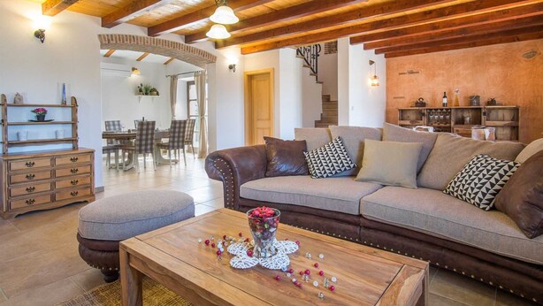 Ein gemütliches Wohnzimmer mit einem braunen Ledersofa, einem Couchtisch mit Dekoration und einer Treppe im Hintergrund.