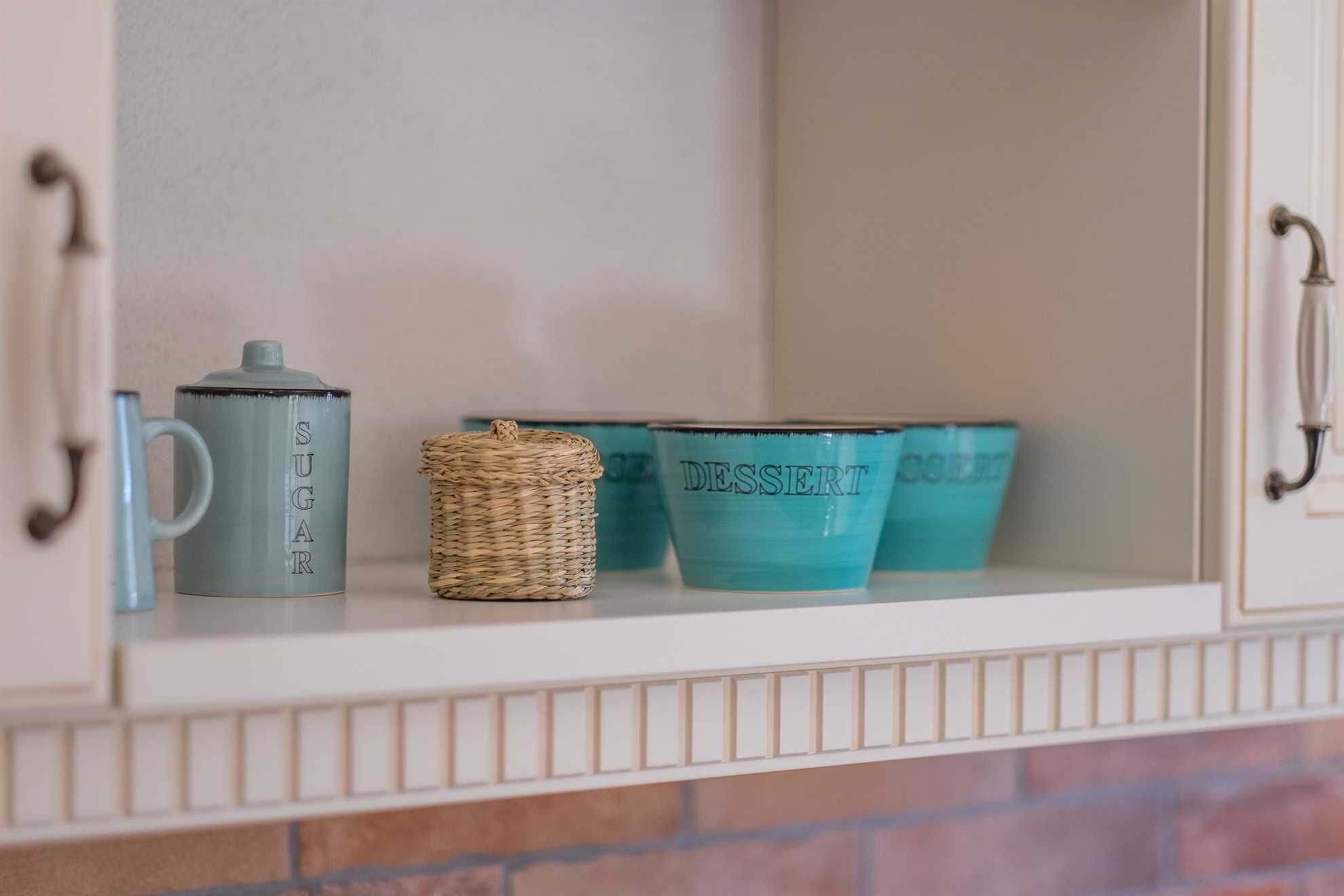 A cabinet shelf with a sugar container, a woven basket, and two dessert cups.