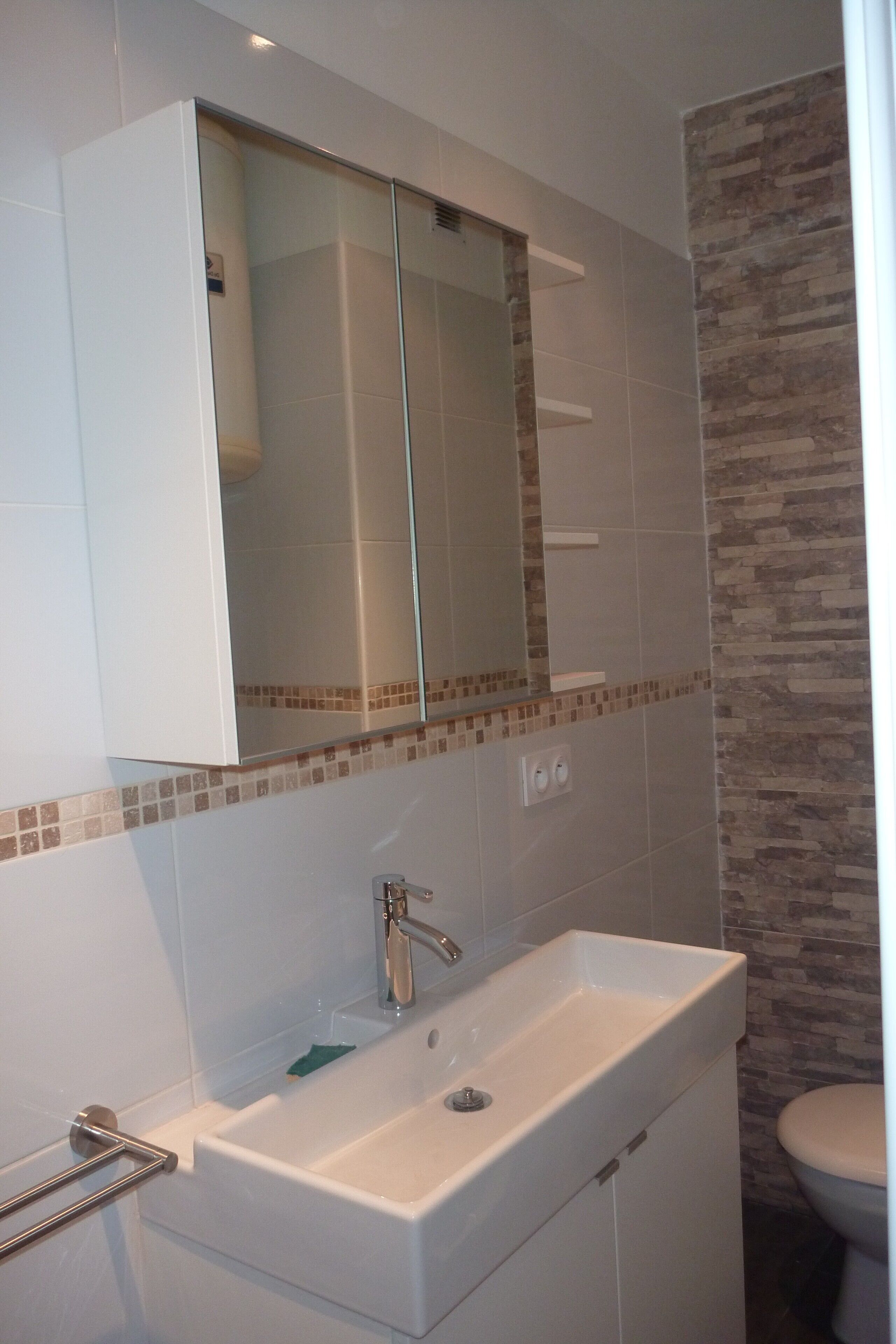 Un baño con lavamanos blanco, espejo y retrete.