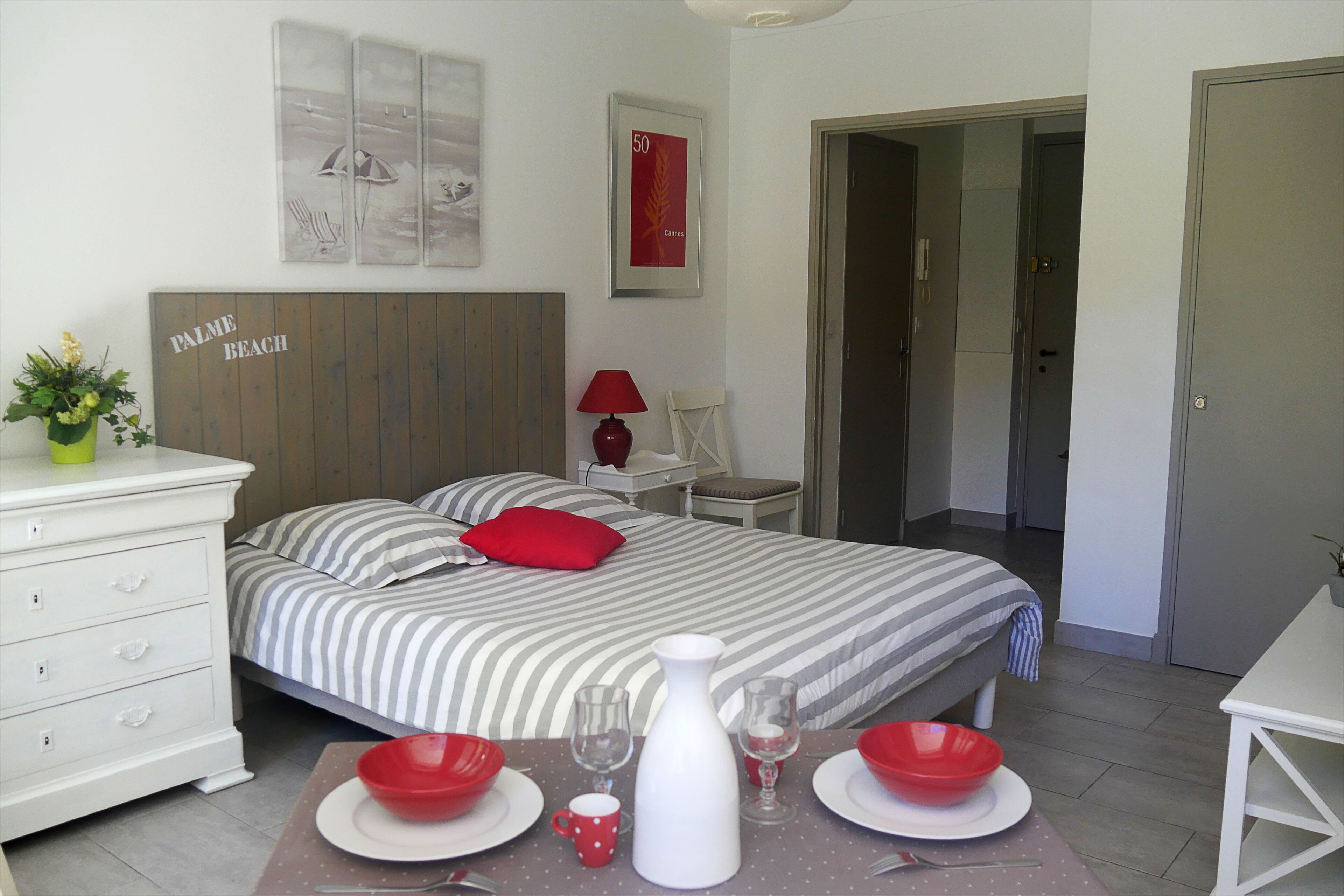 A neatly arranged bedroom with a bed, bedside tables, a nightstand, and a dining area with a table set for two.