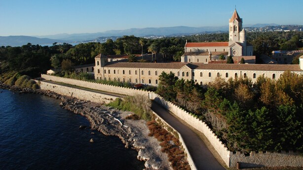 A coastal building with a prominent tower, surrounded by a stone wall and a pathway leading to the entrance. - Bright, air-conditioned studio with garden terrace, in the heart of Cannes (Cannes)