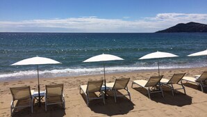 A beach with rows of sun loungers and white umbrellas, facing the ocean. - Bright, air-conditioned studio with garden terrace, in the heart of Cannes (Cannes)