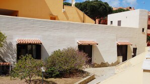 A building with three small windows with terracotta roofs, a small tree, and a stone pathway. - Rent studio apartment  (La Maddalena)