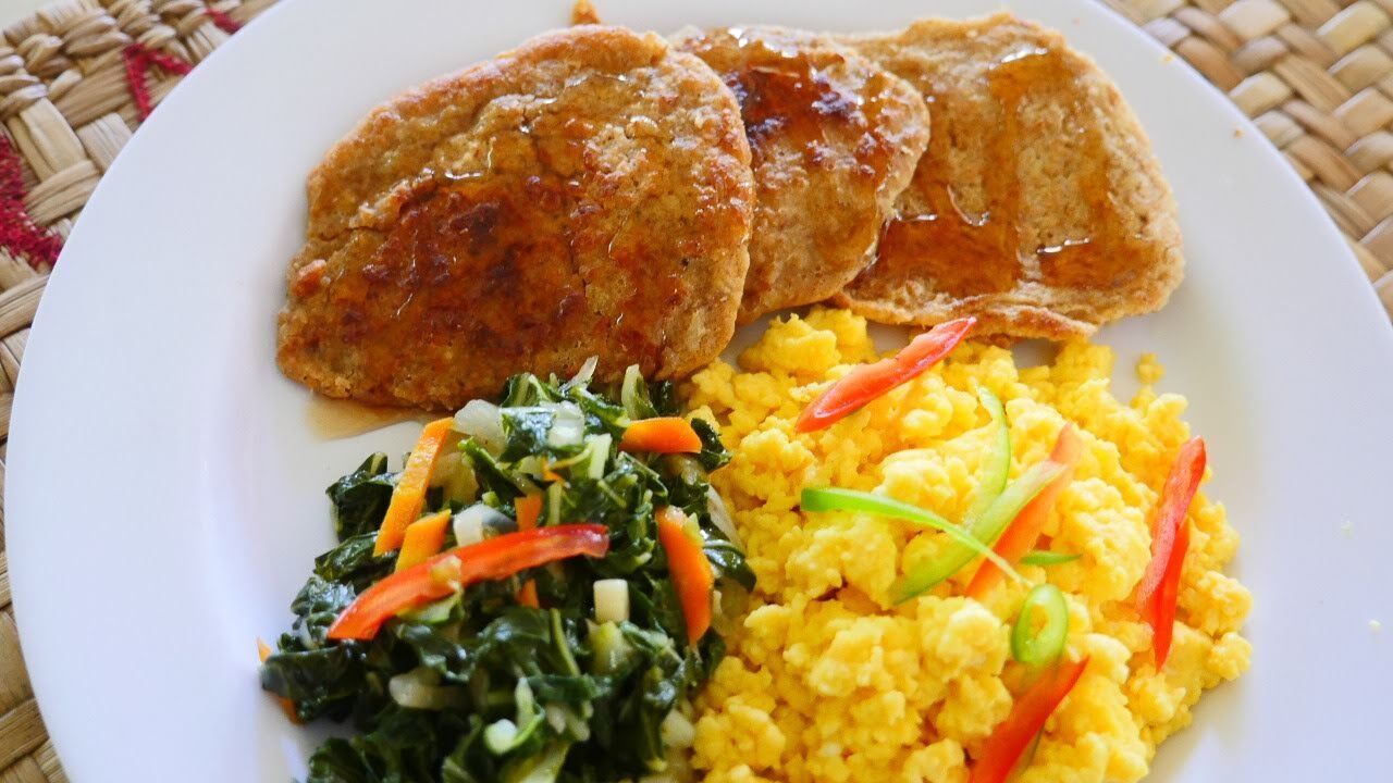 A plate with scrambled eggs, sautéed greens, and two pieces of bread.