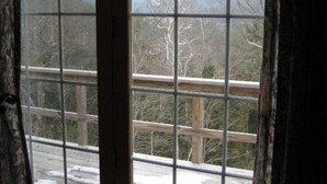 Ein Fenster mit Blick auf eine gebirgige Landschaft und eine Holzbrücke.