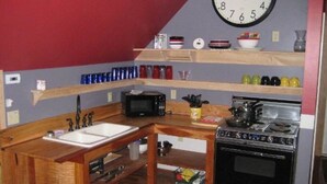 Eine kleine Küche mit Holzausziehtisch, Spüle, Mikrowelle und Herd.