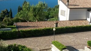 A courtyard with a chessboard, a white building with a tiled roof, and a view of the sea and hills in the background. - # 208 Casa Allegro for 4 people, pool, lake view (Gardola)
