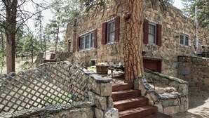 A stone building with red shutters, a wooden staircase, and a metal fence. - Stonehaven Home - Perfect for family getaway #3384 (Estes Park)