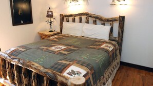 A bed with a rustic wooden headboard, a quilt with animal prints, and wall-mounted lights. - Stonehaven Home - Perfect for family getaway #3384 (Estes Park)