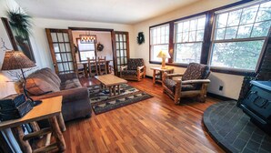 A cozy living room with wooden flooring, a fireplace, and a dining area with wooden chairs and a table. - Stonehaven Home - Perfect for family getaway #3384 (Estes Park)