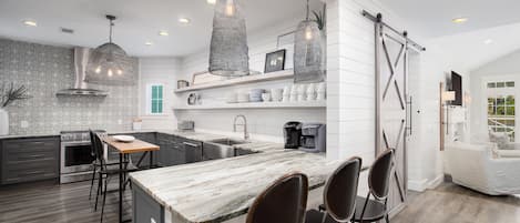 A modern kitchen with a central island, pendant lighting, and a farmhouse-style design.