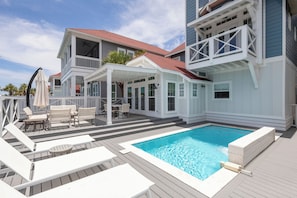 A two-story house with a swimming pool, outdoor furniture, and a covered patio area.