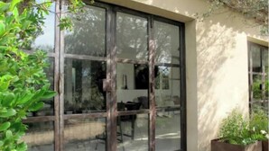Un edificio moderno con grandes puertas de vidrio y un patio con plantas en macetas.