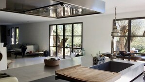 Una cocina moderna con una isla grande, horno empotrado y ventana con vistas a un árbol.