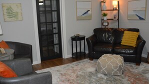 A living room with a black leather sofa, a gray armchair, a small round table, and a decorative rug.