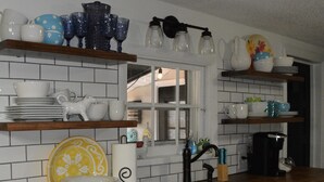 A kitchen with white cabinets, a wooden countertop, and various kitchenware on shelves.