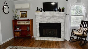 A living room with a fireplace, a television, a bookshelf, and a rocking chair.
