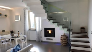 A modern living room with a glass staircase, a fireplace, a dining area, and a sofa. - A newly renovated, stylish 2 bedroom apartment with amazing sea view (Nerano)