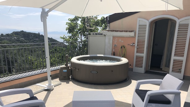 A balcony with a hot tub, white wicker furniture, and a view of the hills. - A newly renovated, stylish 2 bedroom apartment with amazing sea view (Nerano)