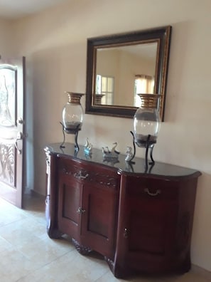 A stylish cabinet with glass-fronted vases and a large mirror above.