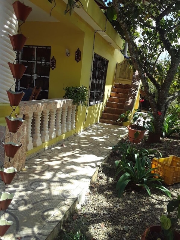 Stroll up the tiled pathway to the entrance of this charming residence, featuring a wooden staircase and a beautifully landscaped garden.