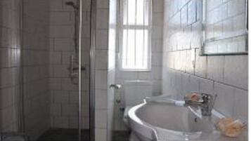 A bathroom with a glass shower enclosure, a bathtub, and a sink with a towel.